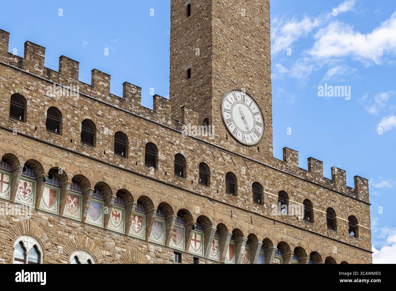 Primo piano della facciata in pietra di Palazzo Vecchio e della torre dell'orologio contro un cielo blu, a Firenze, Italia Foto Stock