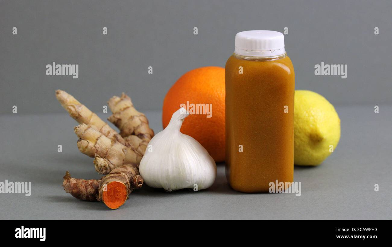 Shot benessere alla curcuma in una bottiglia di plastica con aglio, zenzero, arancia e limone. Disintossicazione e bevanda super-stimolante per la salute naturale. Foto Stock Shot benessere alla curcuma in una bottiglia di plastica con aglio, zenzero, arancia e limone. Disintossicazione e bevanda super-stimolante per la salute naturale. Foto Stock