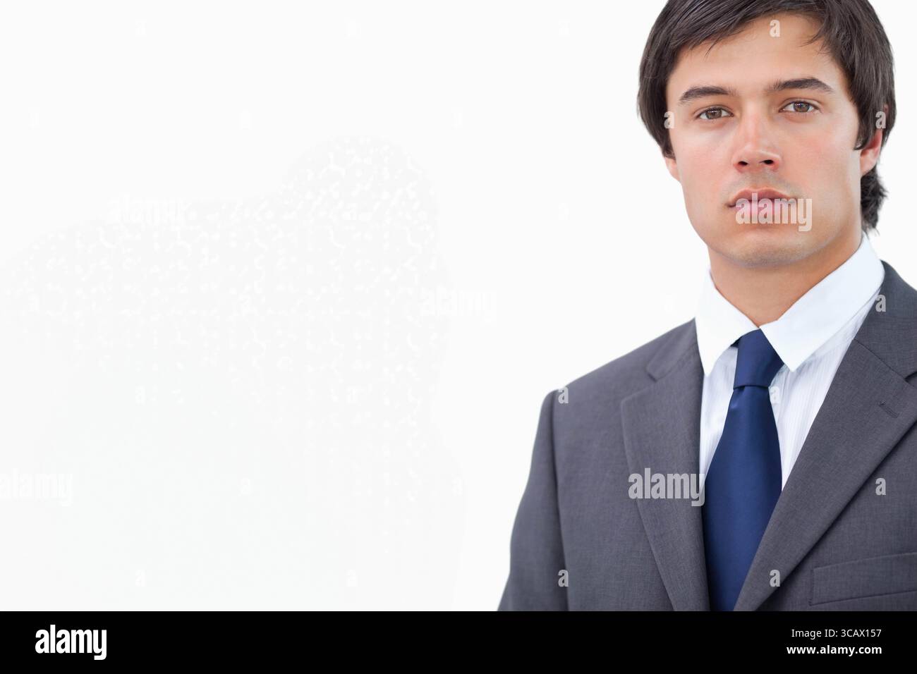 Uomo in piedi con abito grigio, camicia bianca e cravatta blu navy presso lo studio fotografico, copia spazio Foto Stock