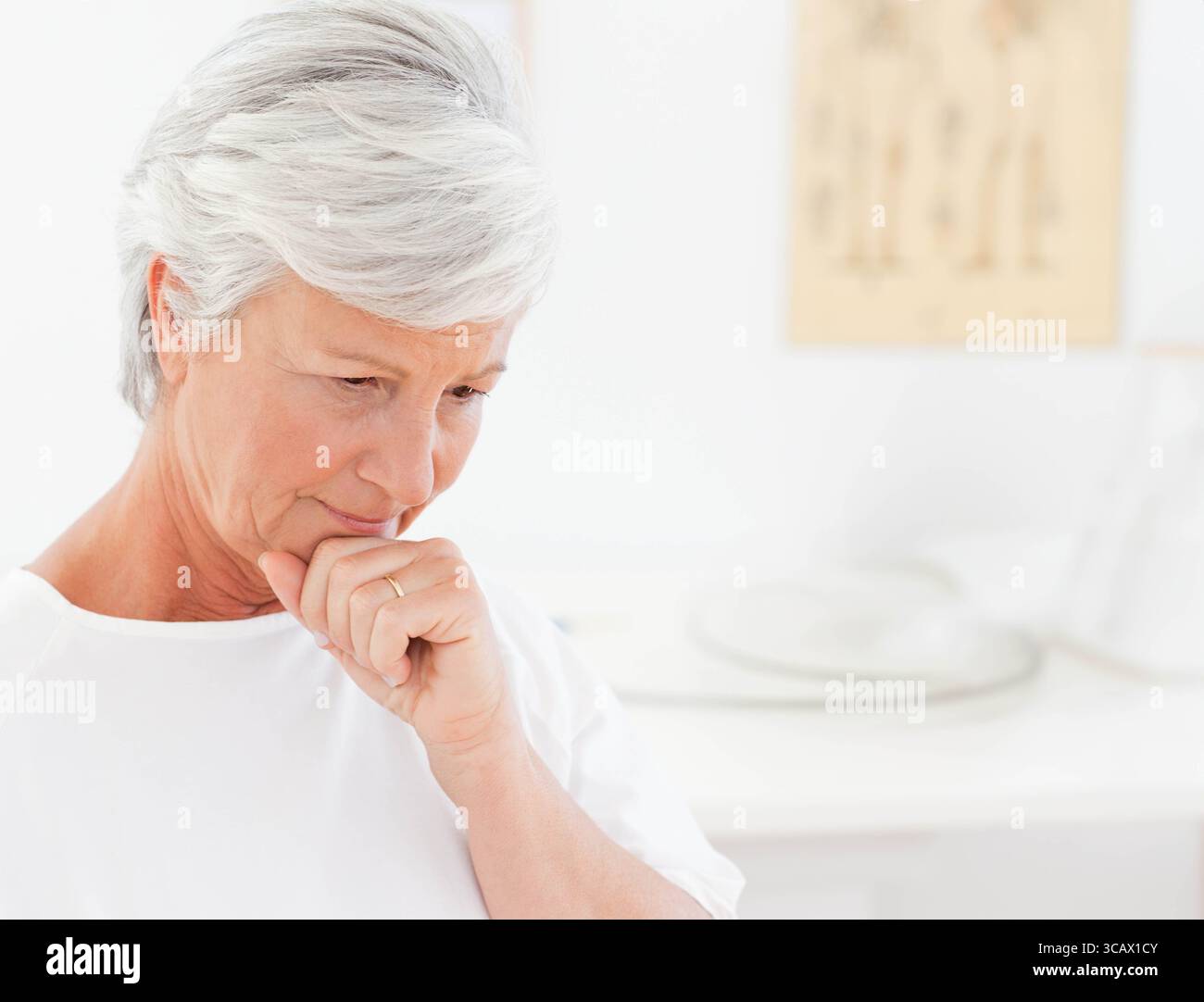 Donna anziana seduta nella sala esame che tocca il labbro con anello dorato sotto la cartella anatomica, spazio per copiare Foto Stock