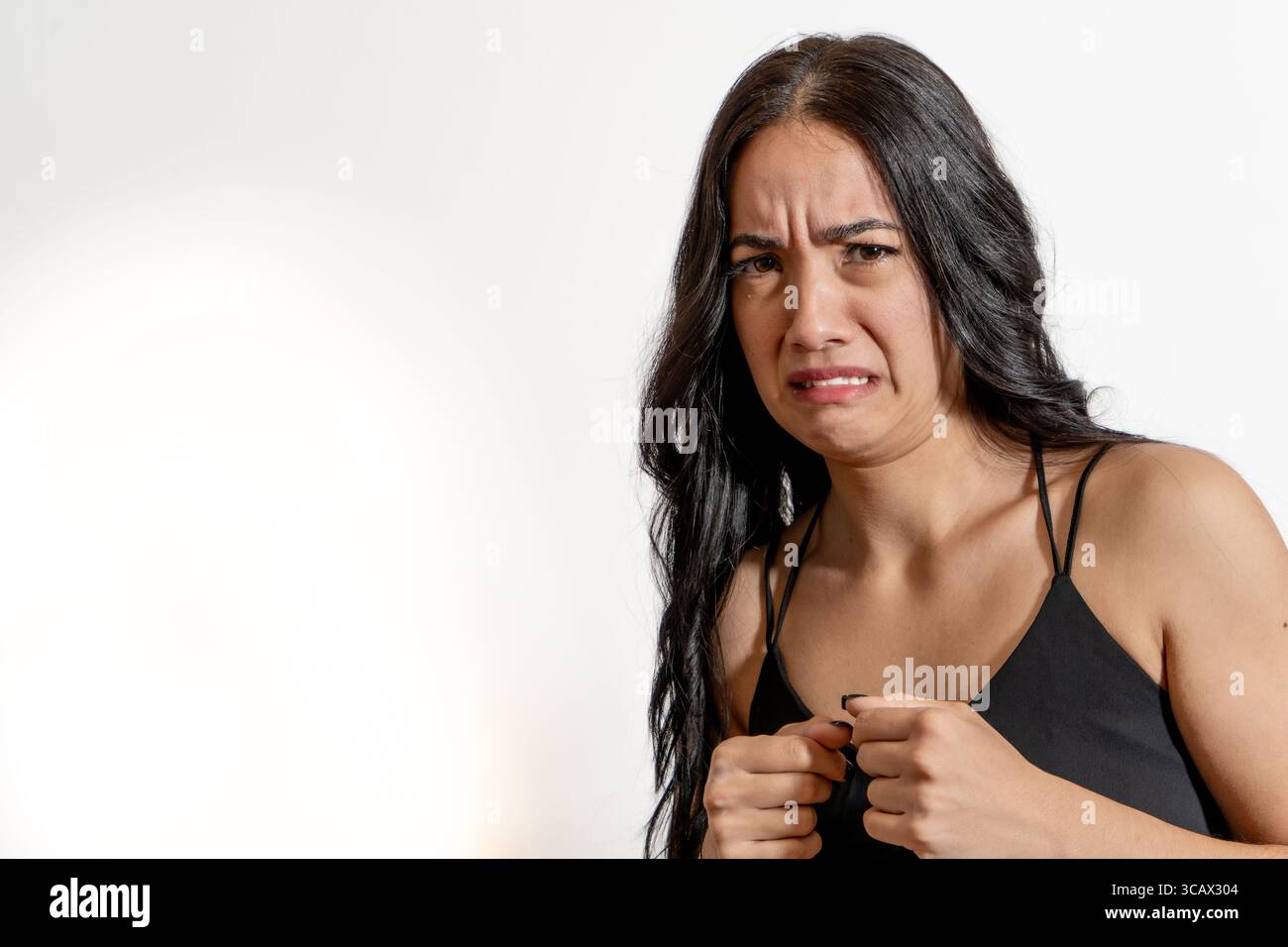 Ritratto in studio di una giovane donna latina che fa una disgustata grima, esprimendo forte avversione o repulsione Foto Stock