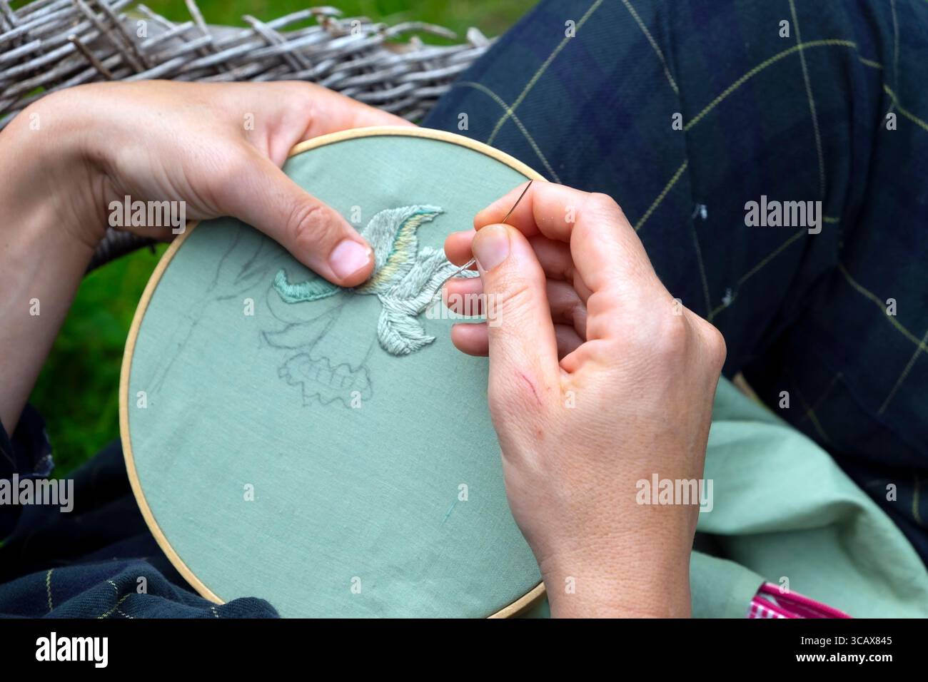 Donna che tiene le mani con filo ad ago ricamo in tessuto verde artigianale Foto Stock