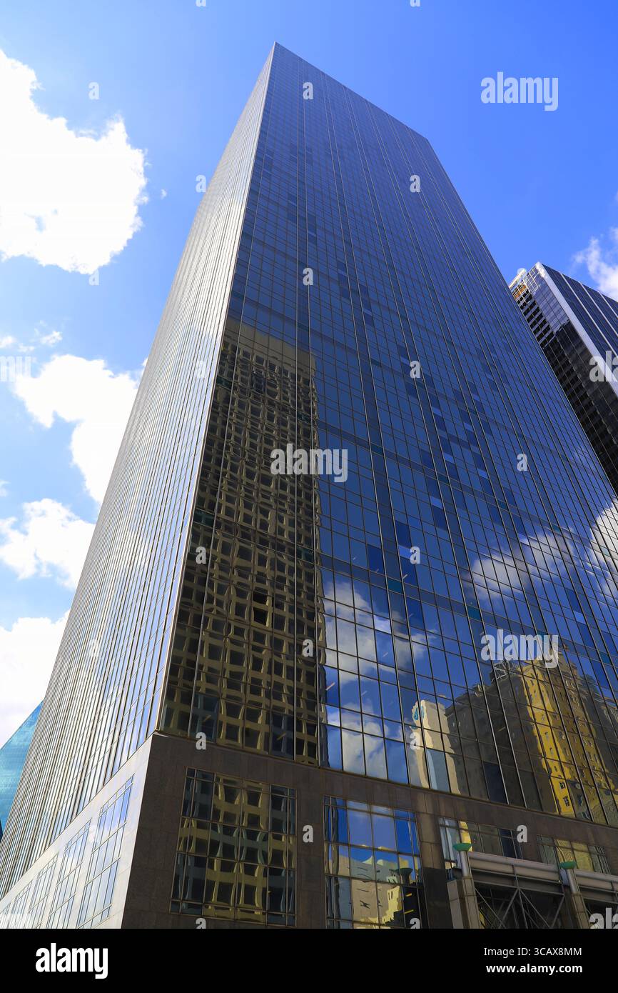 Prospettiva verso l'alto di un alto edificio in vetro con altri edifici che si riflettono nella facciata in vetro Foto Stock