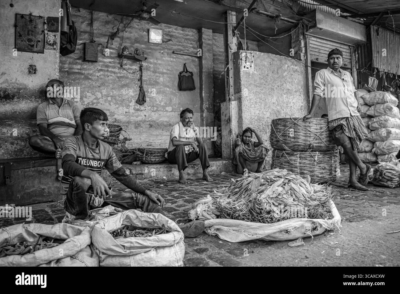 I venditori fanno una pausa tranquilla nel trambusto di un mercato di strada del West Bengal, i loro cesti di prodotti freschi che raccontano la storia della resilienza quotidiana A. Foto Stock