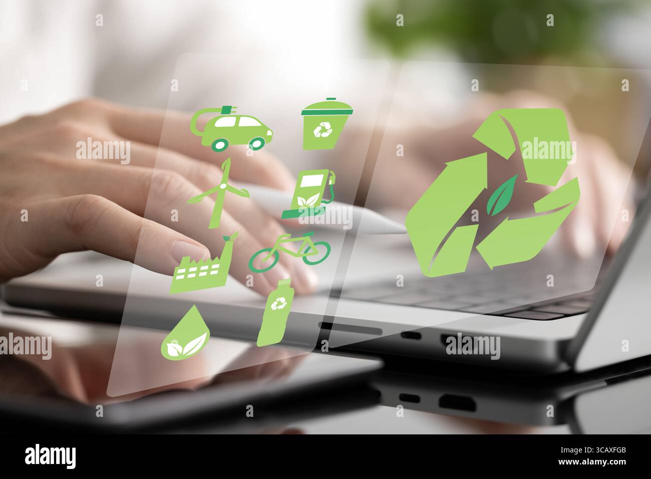Primo piano di un uomo che lavora su un laptop come un ologramma verde che mostra i simboli dell'energia ecologica, del trasporto in bicicletta, del riciclaggio e della purificazione dell'acqua Foto Stock