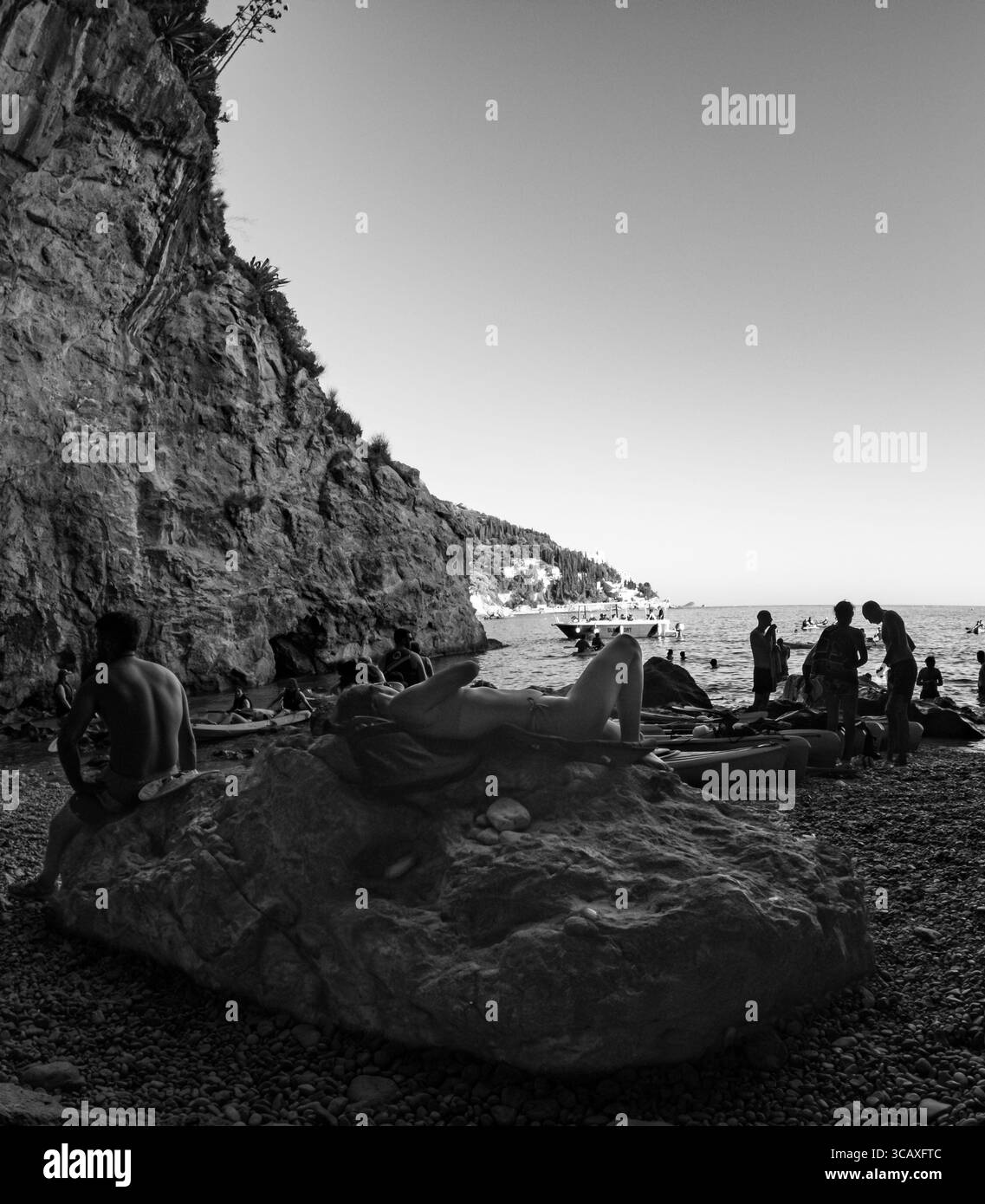 Dubrovnik, Croazia - 12 settembre 2023: I turisti si riuniscono su una spiaggia rocciosa per prepararsi a un tour in kayak al tramonto, godendosi gli ultimi momenti di sole. Foto Stock