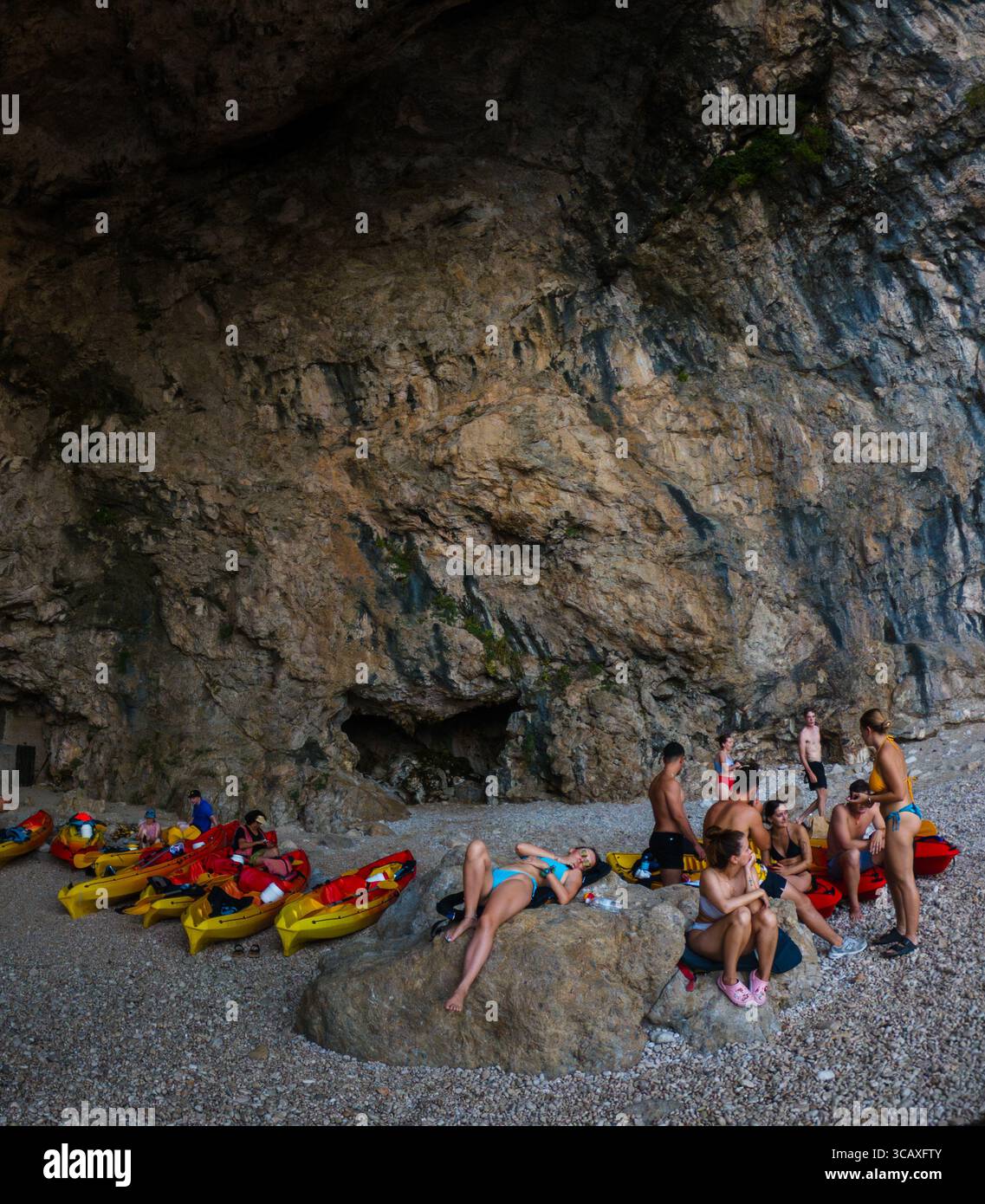 Dubrovnik, Croazia - 12 settembre 2023: I partecipanti al tour in kayak si rilassano su una spiaggia rocciosa durante una pausa. Il gruppo si sta godendo il paesaggio. Foto Stock