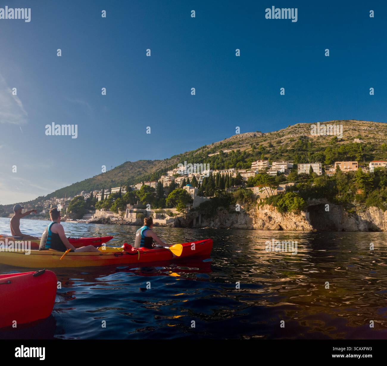 Dubrovnik, Croazia - 12 settembre 2023: I turisti godono di un tour guidato in kayak al tramonto lungo la costa, pagaiando in kayak colorati. Foto Stock