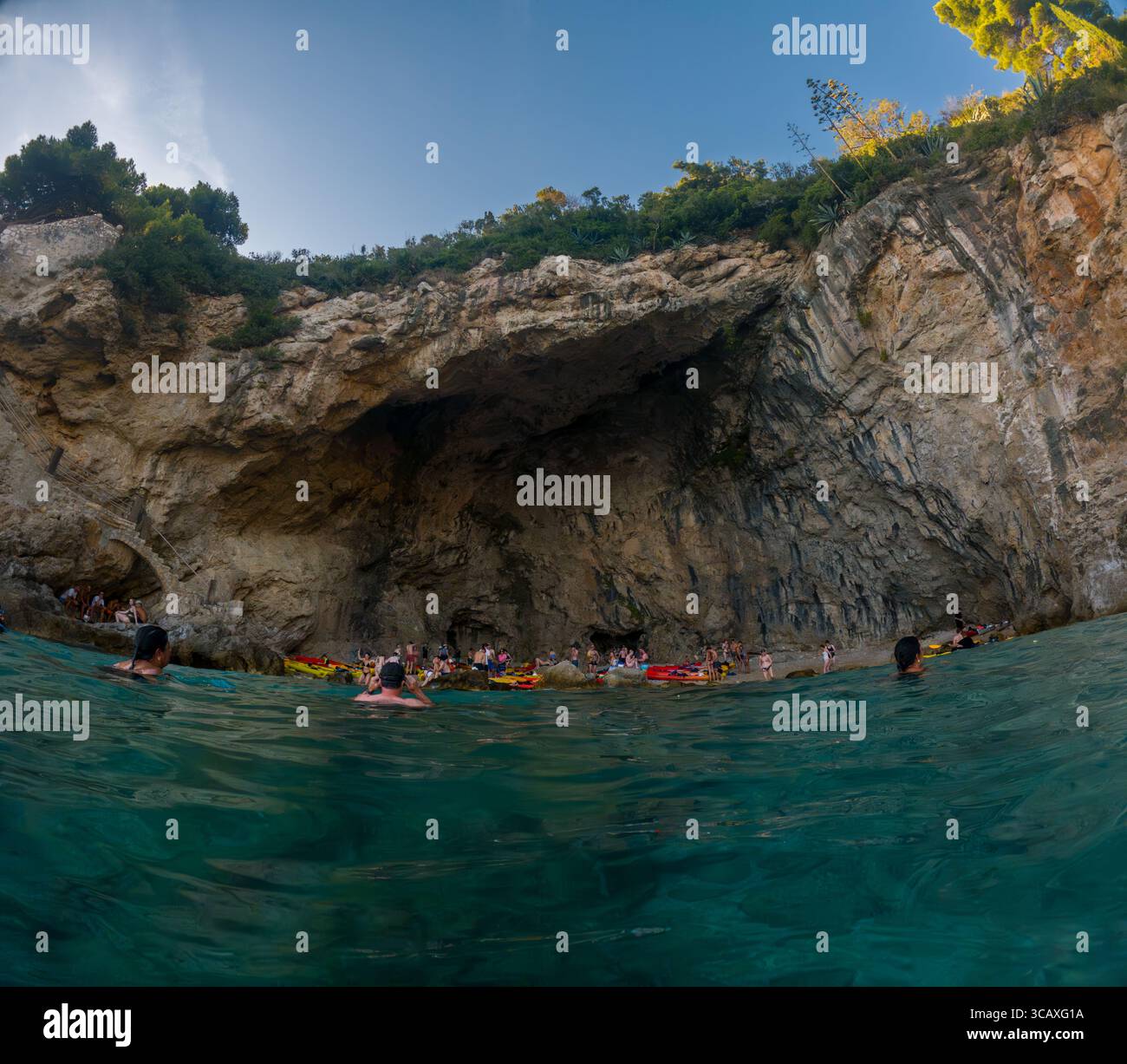 Dubrovnik, Croazia - 12 settembre 2023: I kayak si fermano in una grotta durante un tour al tramonto. Le persone nuotano e si rilassano sulla spiaggia. Foto Stock