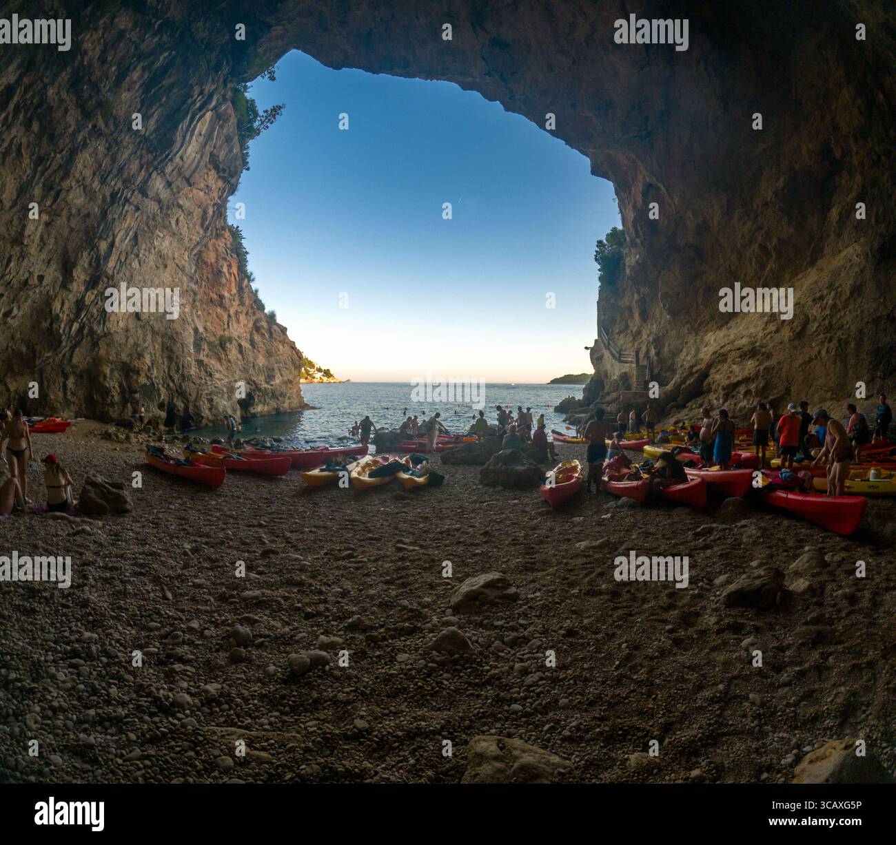 Dubrovnik, Croazia - 12 settembre 2023: I kayak si riuniscono all'interno di una grotta durante un tour al tramonto. La gente sta nuotando e si sta preparando al lancio. Foto Stock