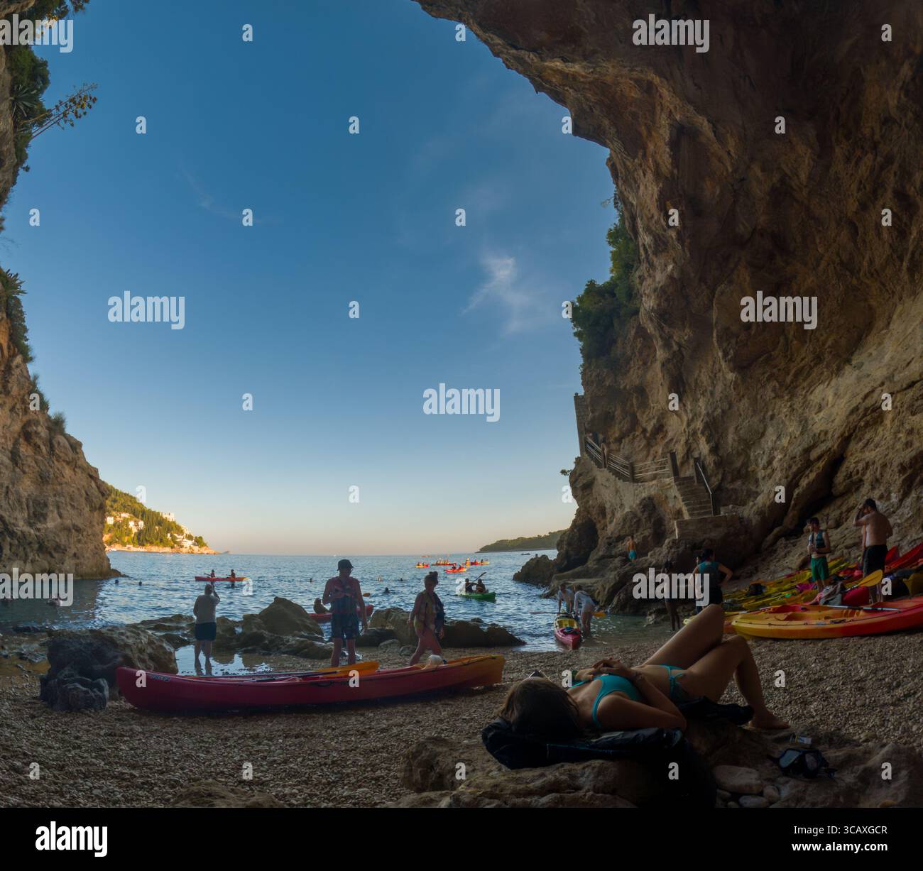 Dubrovnik, Croazia - 12 settembre 2023: I turisti si rilassano dopo un tour in kayak al tramonto, godendosi la spiaggia e il bellissimo paesaggio. Foto Stock