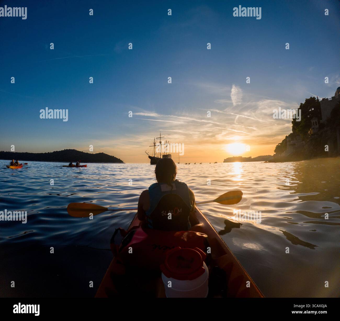 Dubrovnik, Croazia - 12 settembre 2023: I kayaker godono di un tour al tramonto vicino alla costa di Dubrovnik, pagaiando verso una nave storica, creando un memorabile Foto Stock