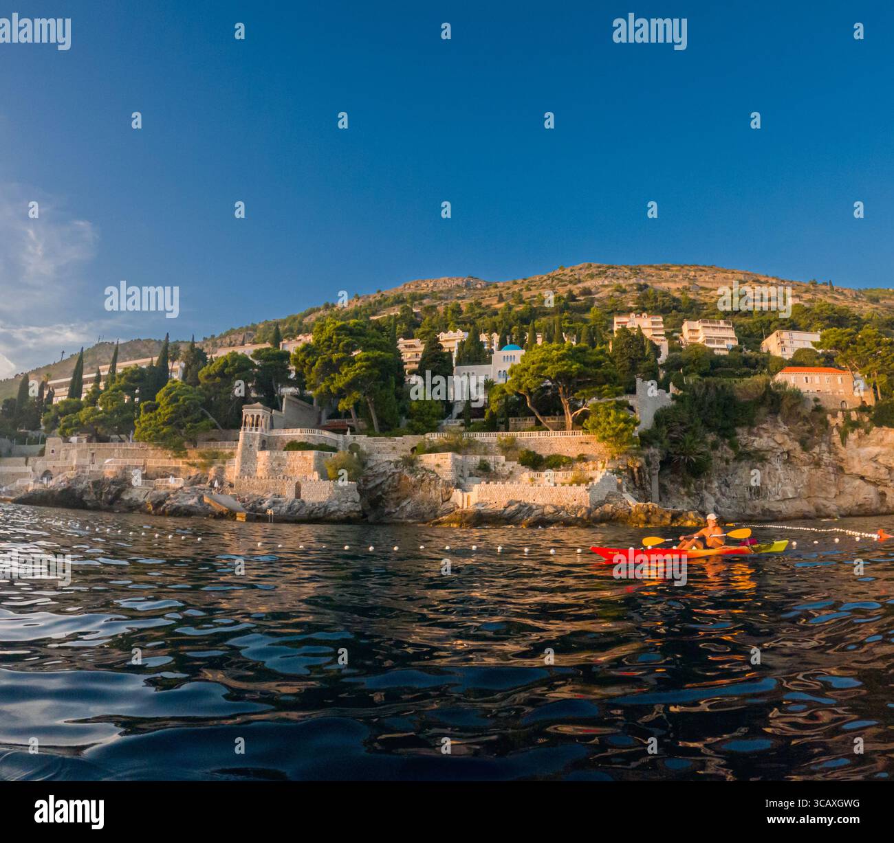 Dubrovnik, Croazia - 12 settembre 2023: Un kayak gode di un tour al tramonto lungo la costa. Le acque calme riflettono la luce dorata. Foto Stock