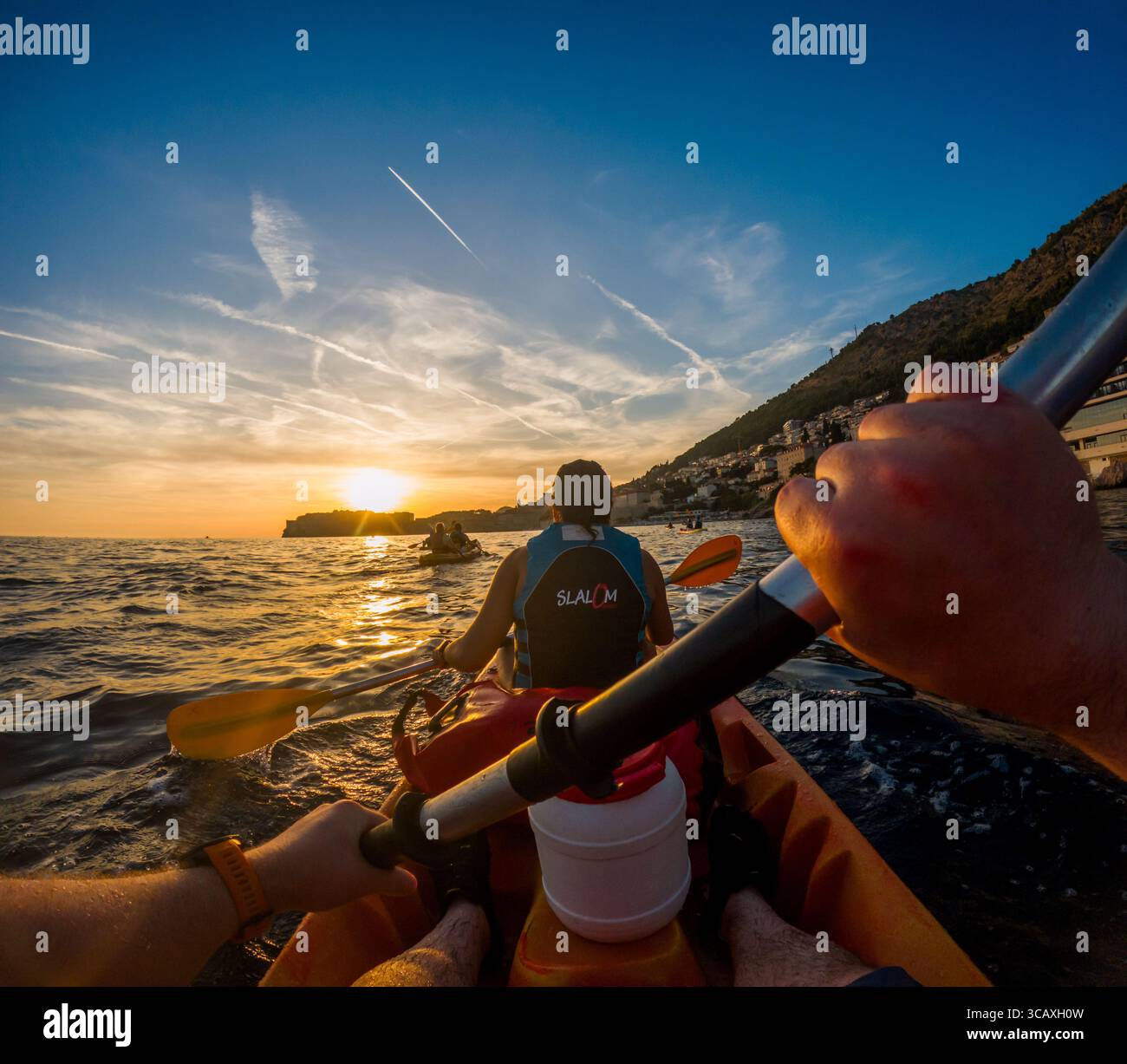 Dubrovnik, Croazia - 12 settembre 2023: I kayak pagaiano al tramonto con un tour guidato. Si godono il bellissimo paesaggio e le acque calme. Foto Stock