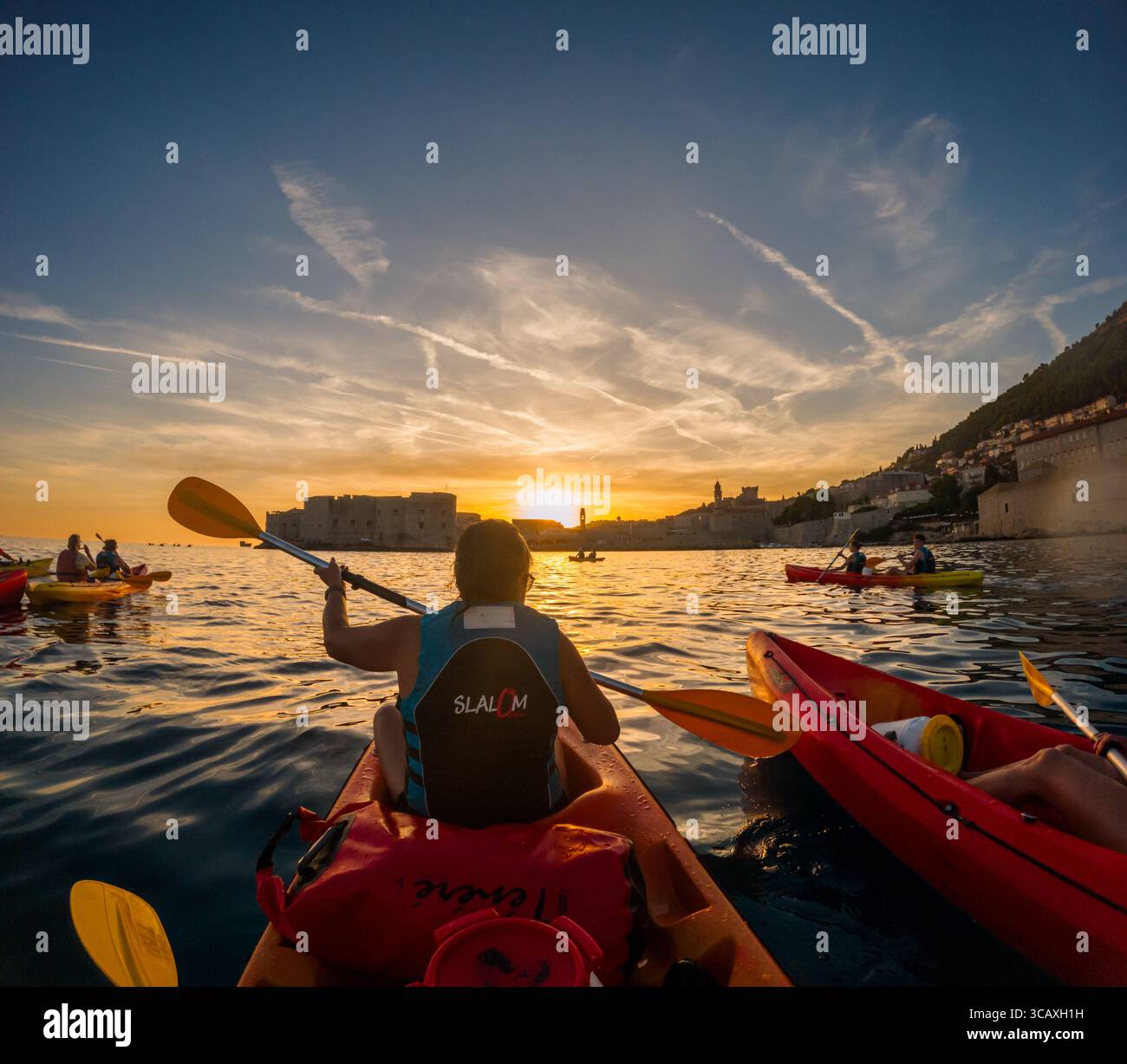 Dubrovnik, Croazia - 12 settembre 2023: I turisti godono di un tour guidato in kayak al tramonto, pagaiando lungo il mare Adriatico vicino alle storiche mura della città. Foto Stock