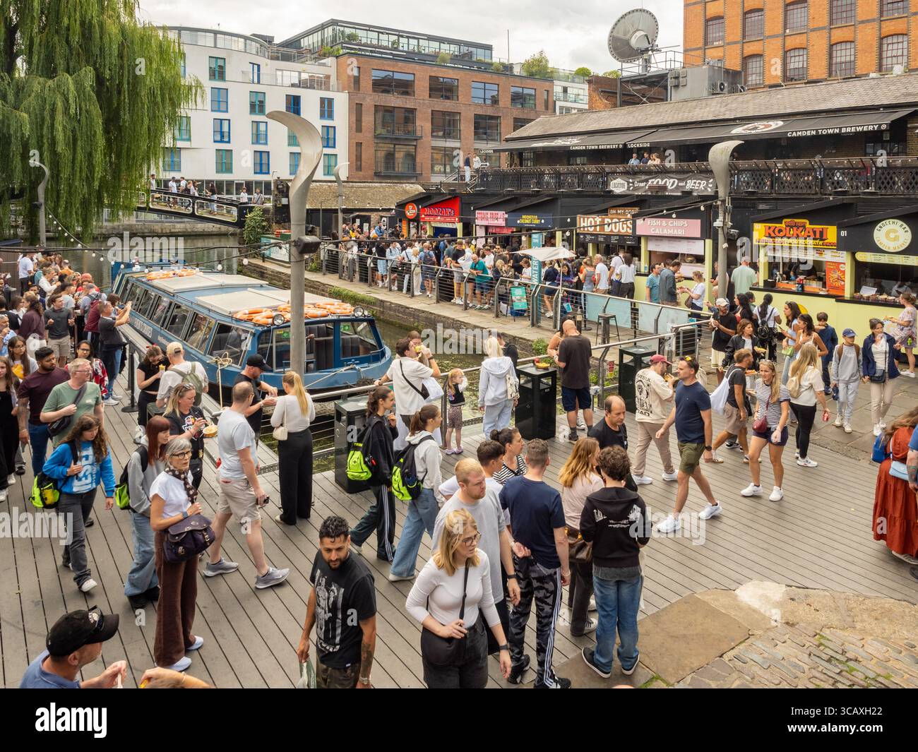 Folle di turisti e locali esplorano le vivaci bancarelle di Street food lungo il Regent's Canal nel famoso mercato di Camden, Londra, Regno Unito. Foto Stock