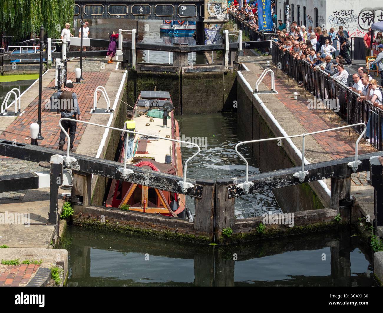 Una vista ad alto angolo di una barca stretta che passa attraverso la famosa chiusa a doppio canale a Camden Lock a Camden Town, Londra, Regno Unito. Foto Stock