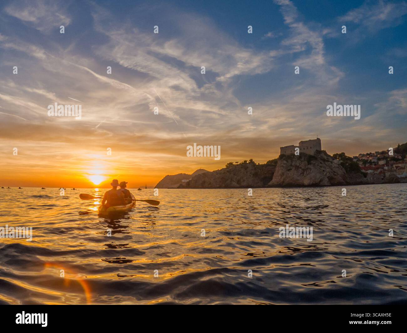 Dubrovnik, Croazia - 12 settembre 2023: I kayak pagaiano al tramonto con un tour guidato. Si godono il bellissimo paesaggio e le acque calme. Foto Stock