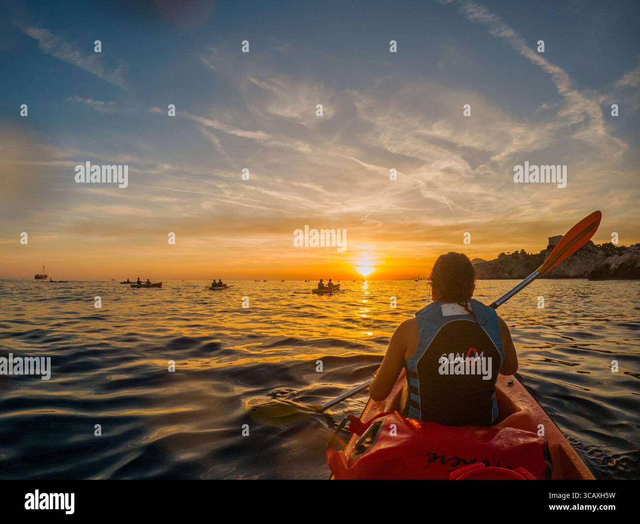 Dubrovnik, Croazia - 12 settembre 2023: I kayak pagaiano al tramonto con un tour guidato. Si godono il bellissimo paesaggio e le acque calme. Foto Stock
