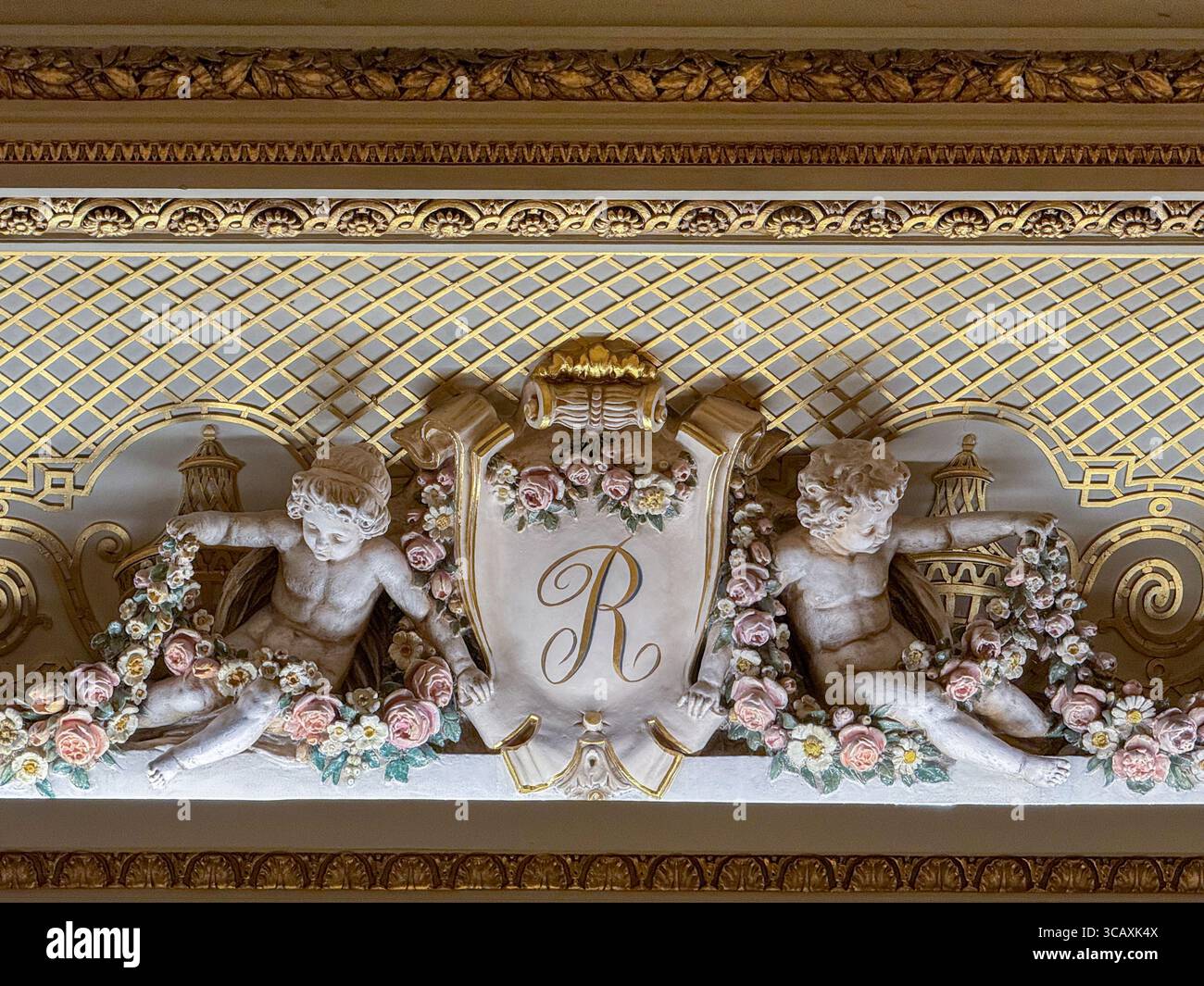 Dettaglio di un cartiglio decorato in gesso dorato con cherubini e la lettera "R" nell'opulenta Palm Court dell'hotel Ritz, Londra, Regno Unito. Foto Stock