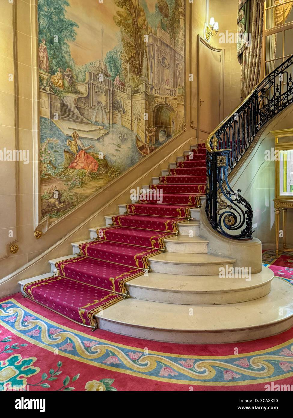 Una grande scalinata in marmo con un lussuoso tappeto rosso e balaustra ornata, all'interno del famoso hotel Ritz a Londra, Regno Unito. Foto Stock