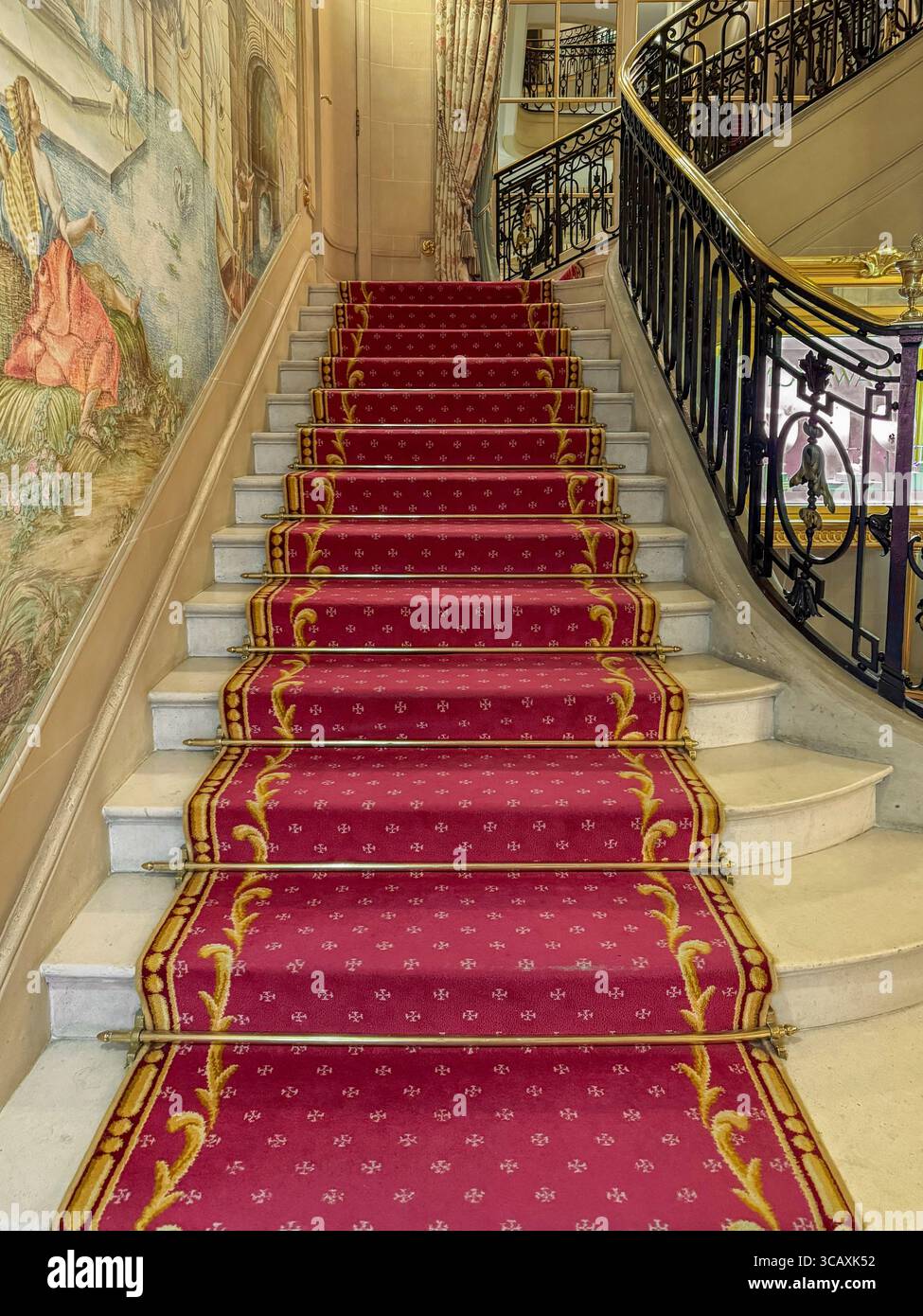 Si affaccia sull'elegante scalinata in marmo con il suo tappeto rosso personalizzato all'interno del famoso hotel Ritz a Mayfair, Londra, Regno Unito. Foto Stock