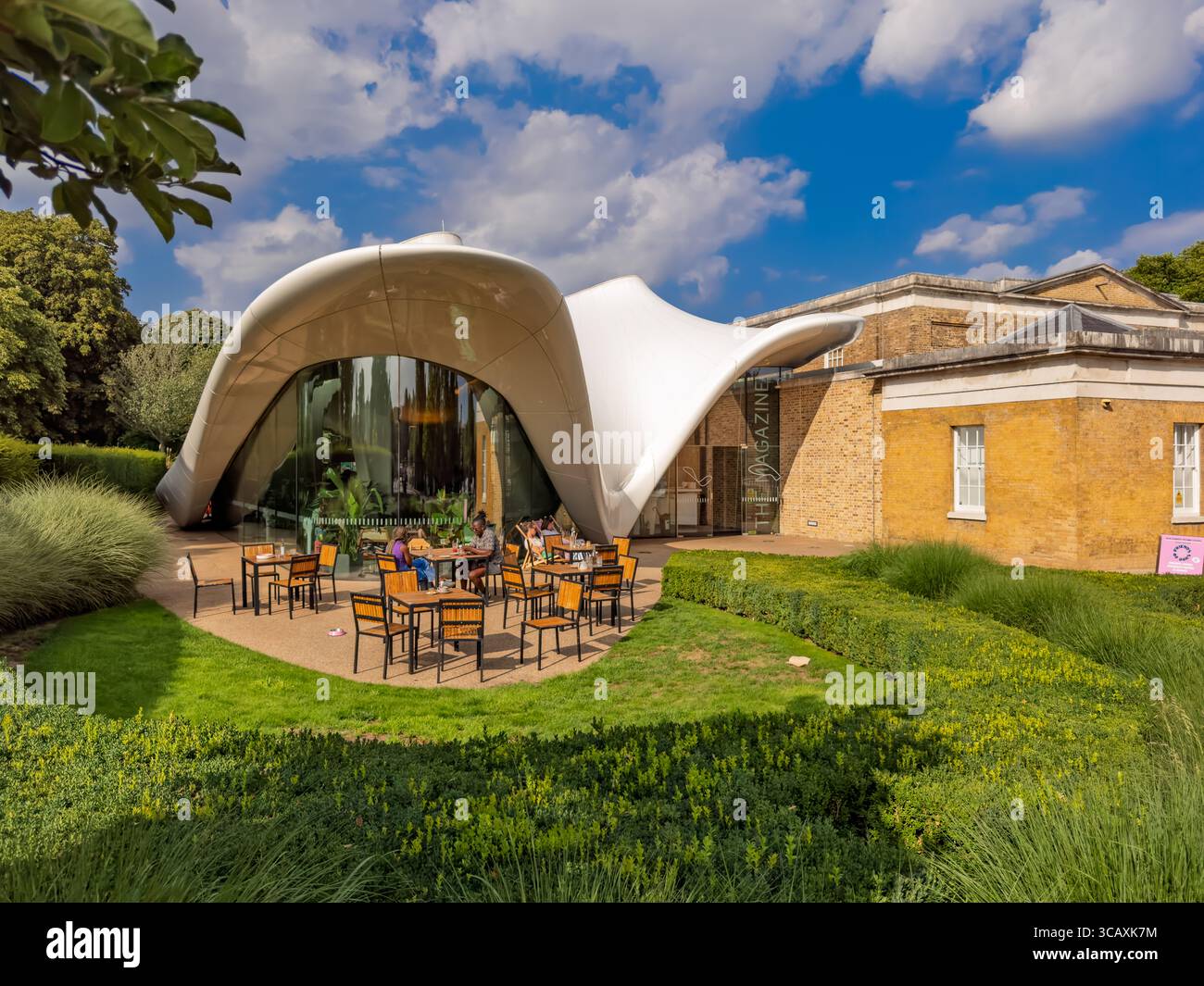 Le persone cenano fuori dal ristorante 'The Magazine' presso la Serpentine North Gallery, nell'estensione moderna progettata da Zaha Hadid, Londra, Regno Unito. Foto Stock