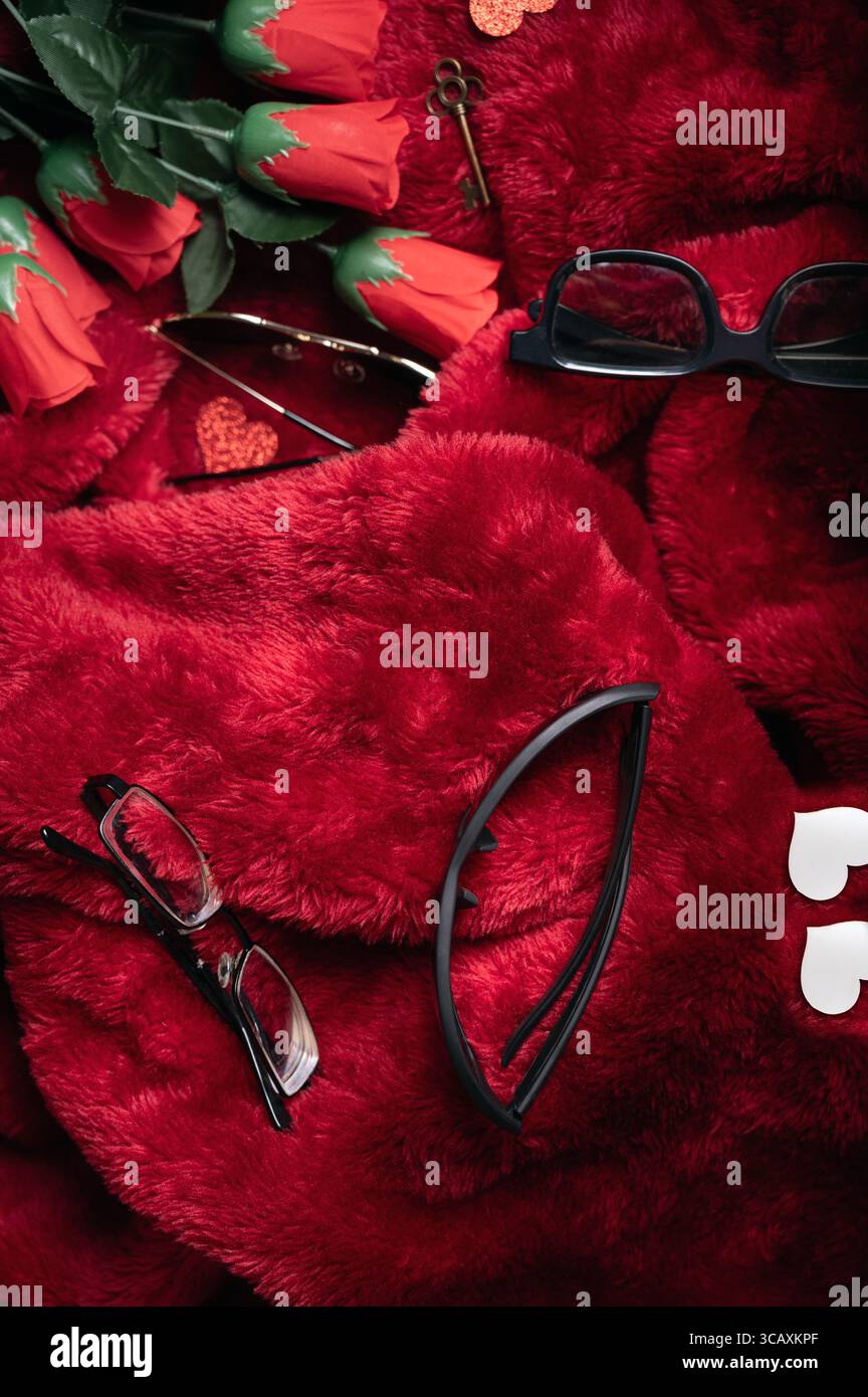 Scena ottica di San Valentino, composizione verticale di strumenti ottici (occhiali, astuccio, lenti) con rose rosse. spazio per il testo. Foto Stock