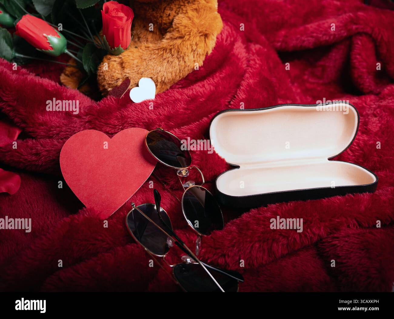 Occhiali per la visione e una custodia aperta su sfondo rosso. Pubblicità per un negozio di ottica. Il concetto di visione di San Valentino in Optometria Foto Stock