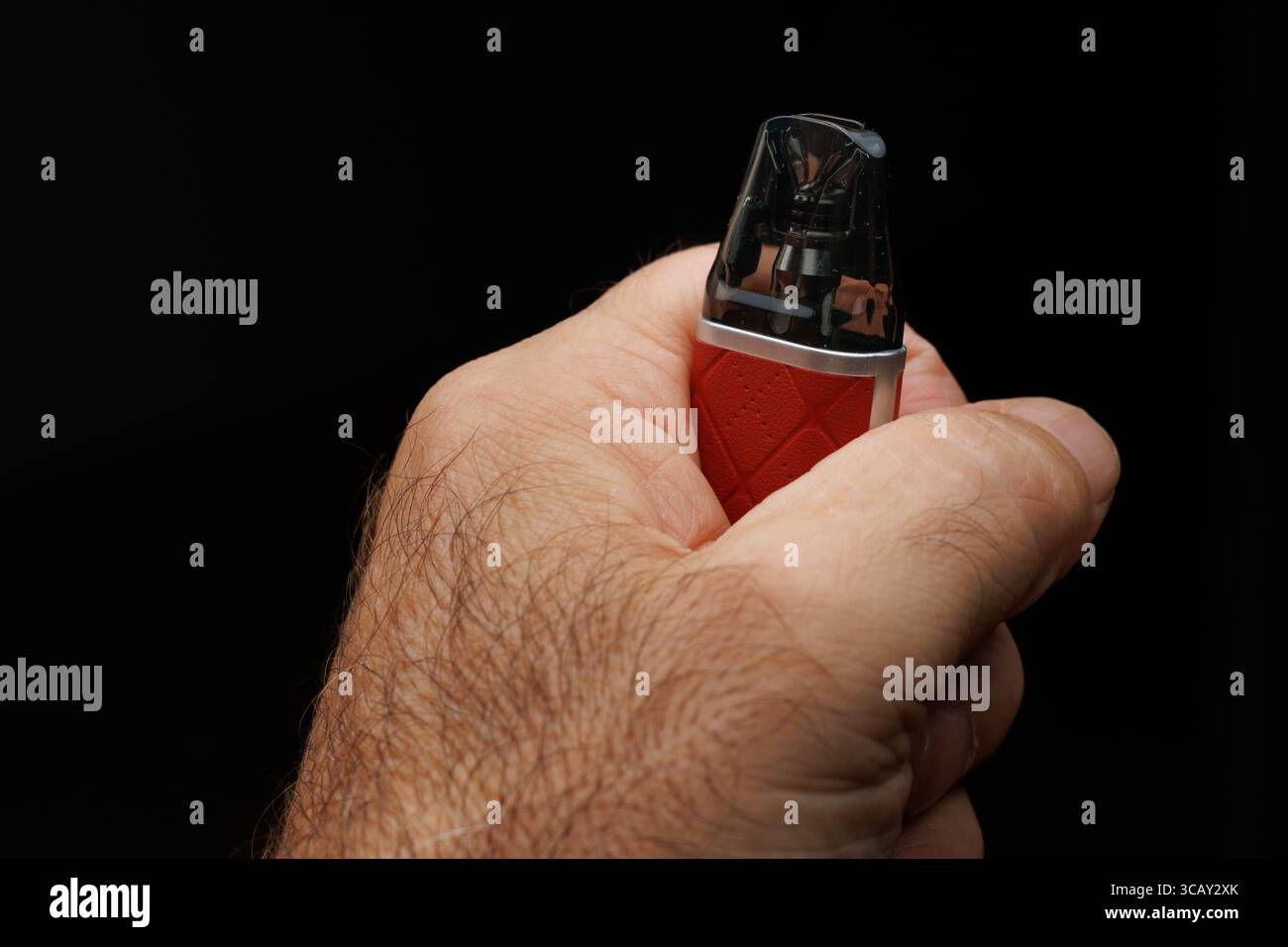 Mano di una persona irriconoscibile che tiene la sigaretta elettronica su sfondo nero Foto Stock