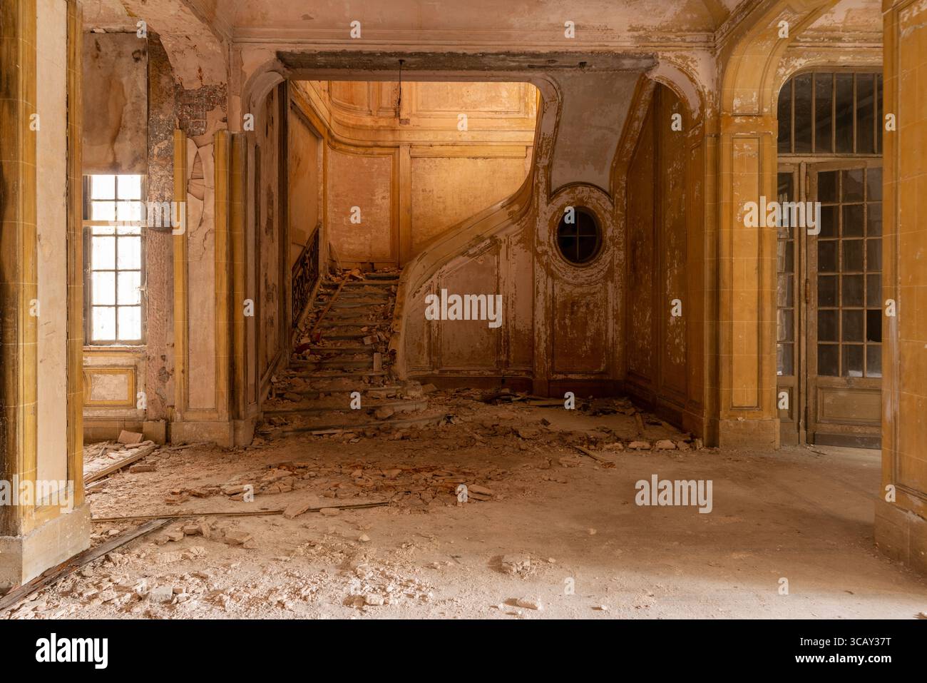 Interno di un edificio abbandonato e in decadenza con una scala rotta e pareti sbucciate, che mostrano l'esplorazione urbana e l'architettura dimenticata Foto Stock