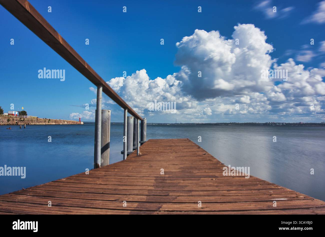 Molo in legno sull'acqua calma con nuvole drammatiche - tranquilla scena costiera Foto Stock