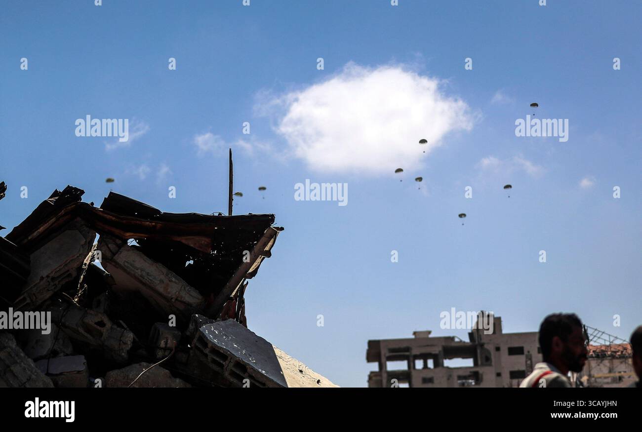 Gaza, Gaza. 7 agosto 2025. Gli aerei rilasciano aiuti con paracadute in mezzo agli attacchi israeliani, mentre i palestinesi si radunano nella zona in cui gli aiuti umanitari atterrano in cima alle case distrutte nella parte occidentale di Gaza, Gaza, giovedì 7 agosto 2025. Foto di Mahmoud Issa/UPI credito: UPI/Alamy Live News Foto Stock Gaza, Gaza. 7 agosto 2025. Gli aerei rilasciano aiuti con paracadute in mezzo agli attacchi israeliani, mentre i palestinesi si radunano nella zona in cui gli aiuti umanitari atterrano in cima alle case distrutte nella parte occidentale di Gaza, Gaza, giovedì 7 agosto 2025. Foto di Mahmoud Issa/UPI credito: UPI/Alamy Live News Foto Stock