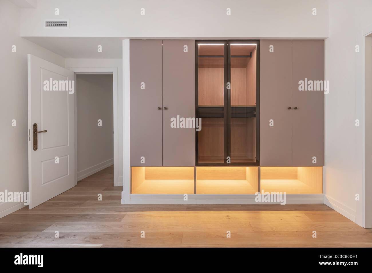 Composizione verticale: Alto armadio in legno laccato bianco con strisce orizzontali in vetro e cassettiera incorporata Foto Stock