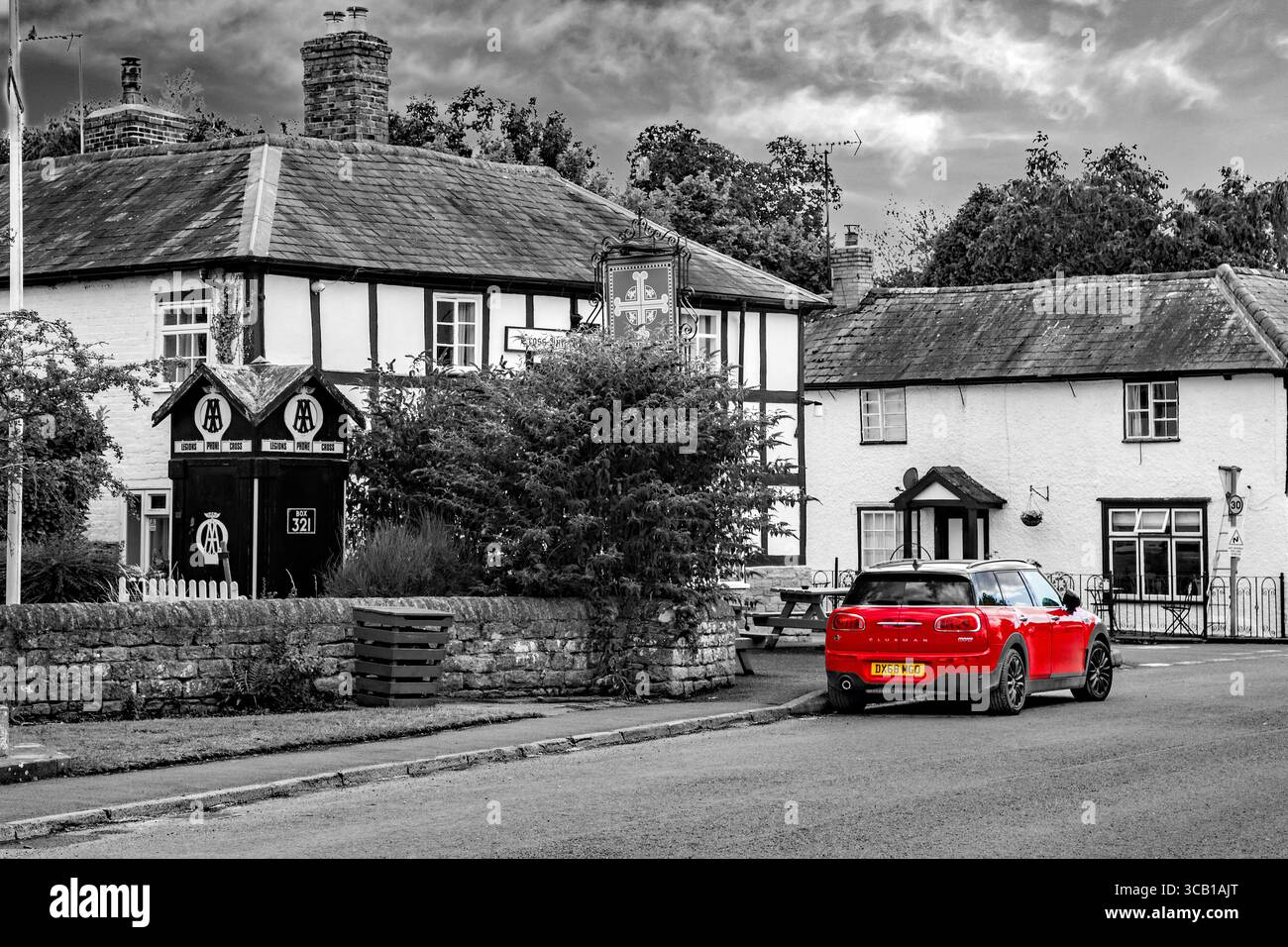 Mini auto rossa parcheggiata nel villaggio bianco e nero di Eardisland, vicino a Leominster, nell'Herefordshire, sulla pista bianca e nera Foto Stock