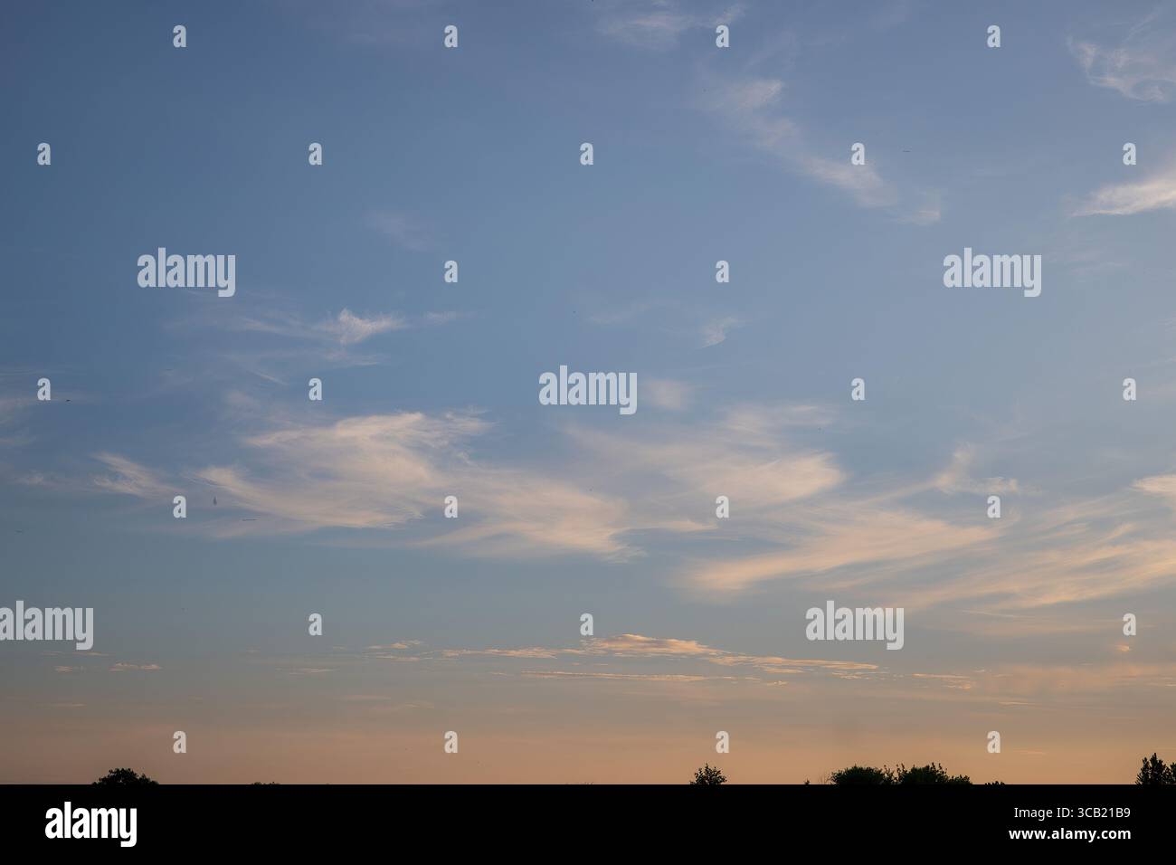 Cielo morbido al tramonto con tonalità dorate e blu e nuvole mostruose. Sfondo panoramico naturale per design, viaggi, relax o temi meteorologici. Foto Stock Cielo morbido al tramonto con tonalità dorate e blu e nuvole mostruose. Sfondo panoramico naturale per design, viaggi, relax o temi meteorologici. Foto Stock