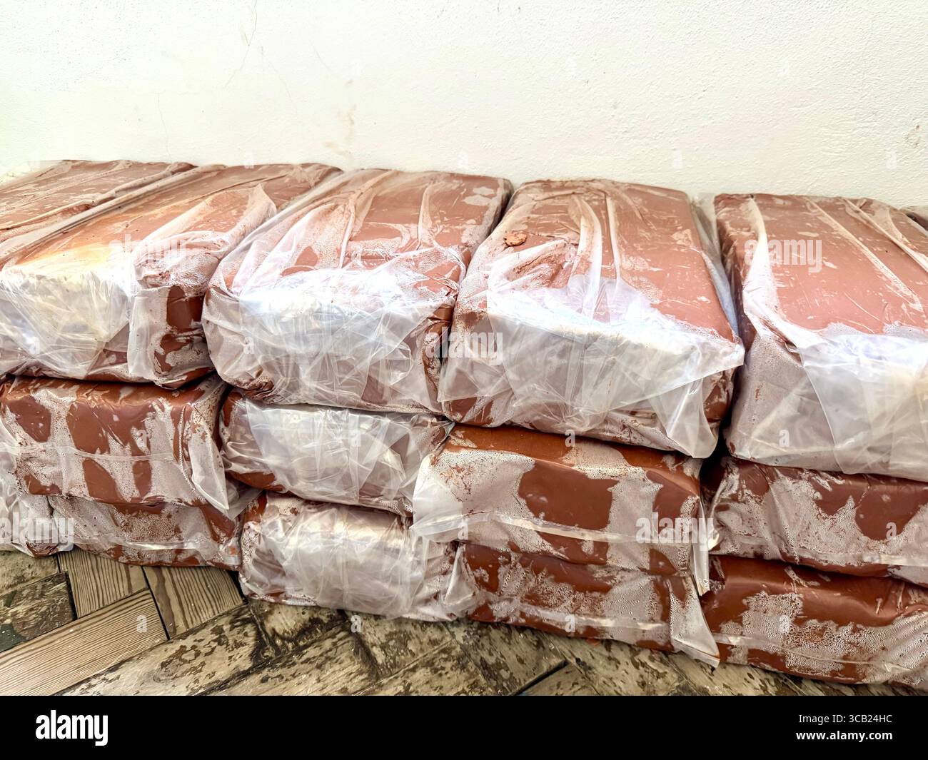 Pile di blocchetti di argilla rossa confezionati in plastica, pronti per l'uso in ceramica o nelle costruzioni. - Immagine stock catturata con smartphone