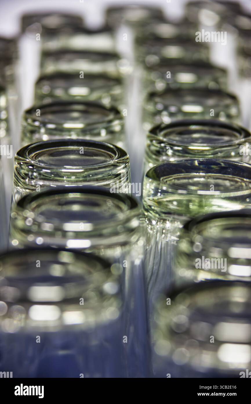 Molti bicchieri d'acqua vuoti posti su un tavolo, sfondo astratto, preparati per gli ospiti per cenare al ristorante. Profondità di campo ridotta, gli occhiali si impilano Foto Stock
