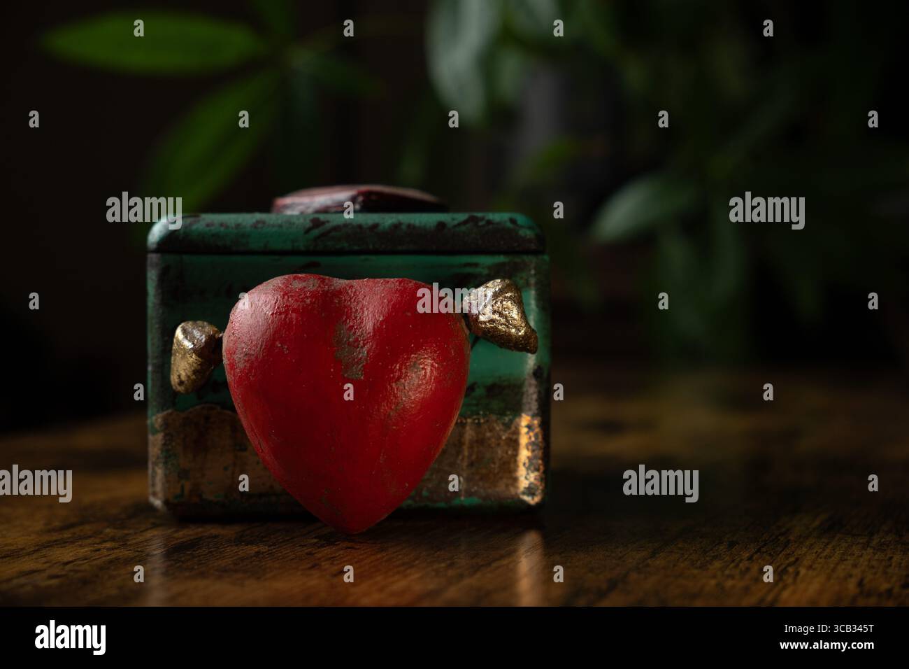 Portagioie decorato in verde e un cuore rosso con ali. Foto Stock