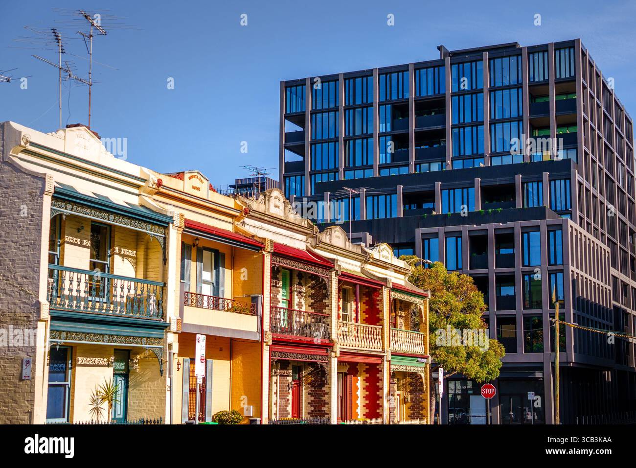 Fila di storiche case a schiera con facciate colorate accanto ad un moderno complesso di appartamenti neri Foto Stock