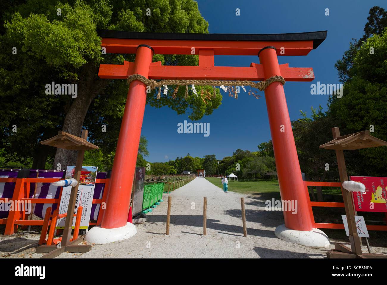 Esplora la suggestiva porta rossa di Ichi no Torii situata sotto gli alberi verdi. Questo iconico ingresso invita alla tranquillità e all'apprezzamento culturale Foto Stock