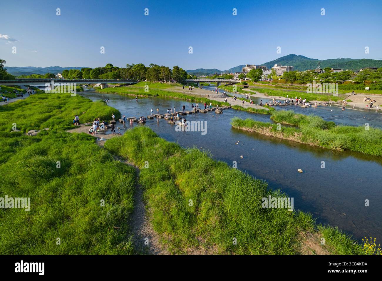 Il Delta di Kamogawa con gente che si rilassa. I dintorni lussureggianti e verdi con montagne lontane offrono un ambiente sereno e pittoresco, perfetto per escursioni Foto Stock