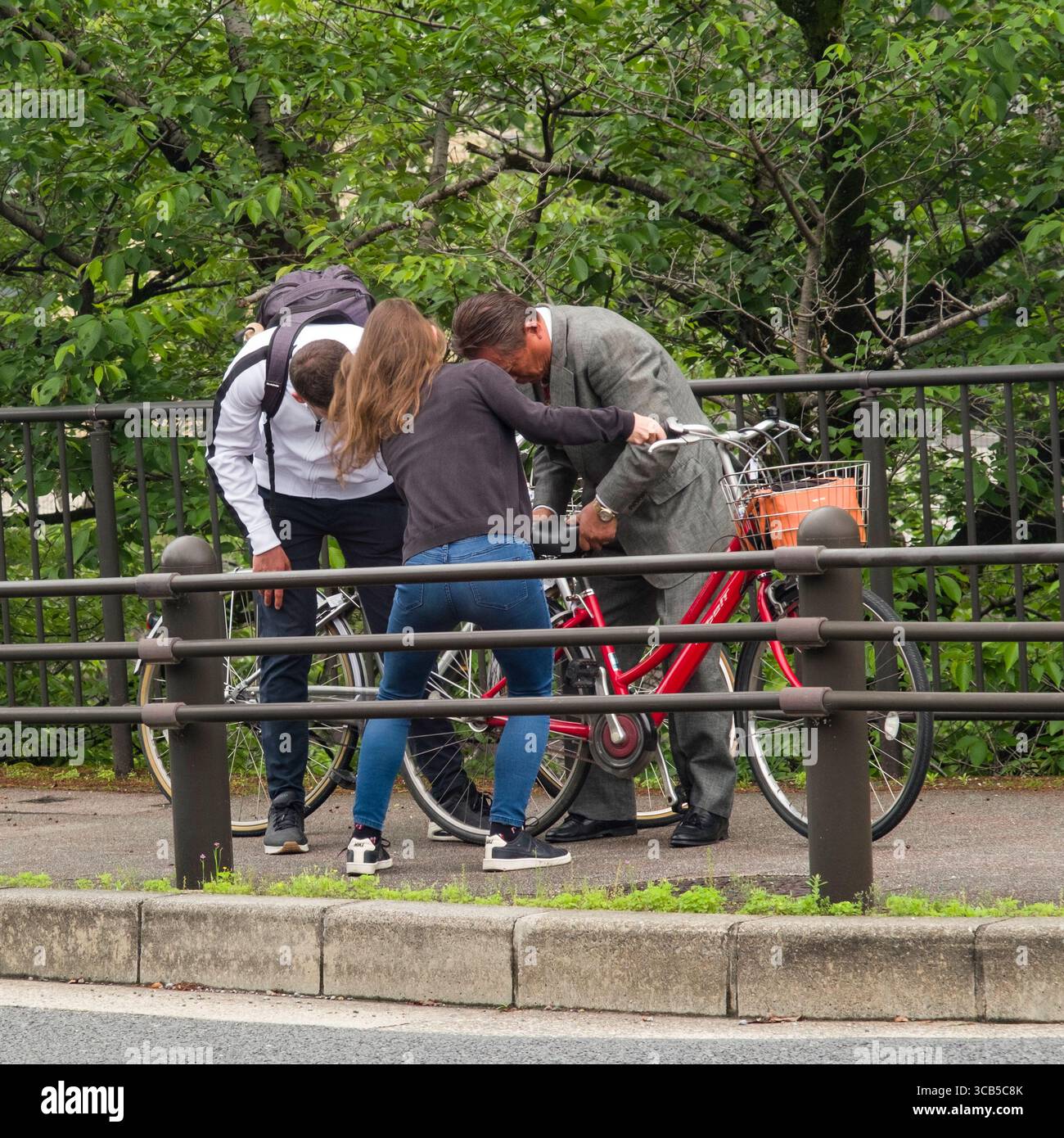 Uomo giapponese che aiuta il turista ad adattare le proprie biciclette a noleggio in una strada cittadina. Il loro impegno collaborativo dimostra il lavoro di squadra e lo spirito della comunità in un Foto Stock
