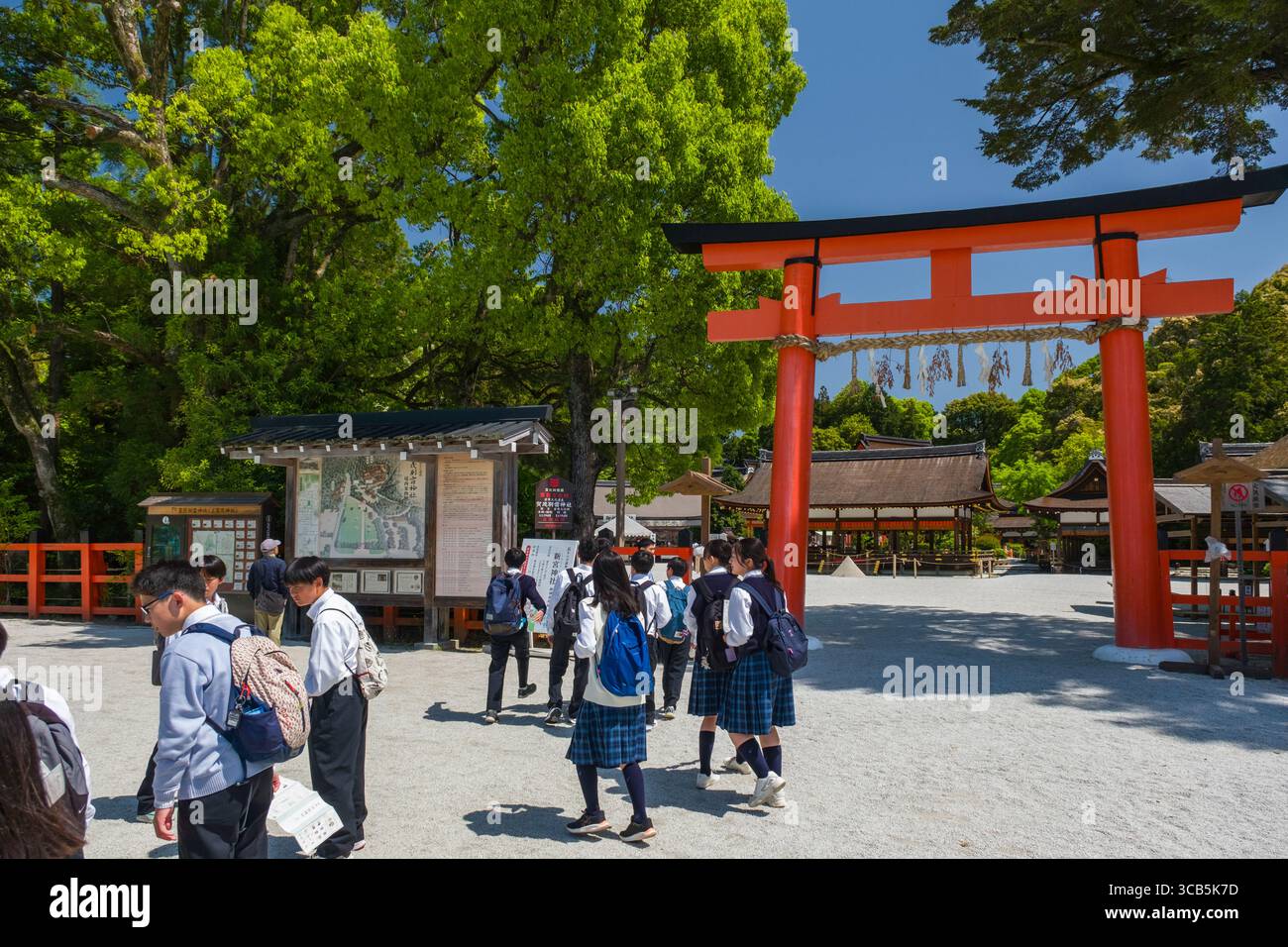 Un gruppo di studenti esplora il santuario di Kamigamo circondato da una vegetazione lussureggiante in una giornata di sole, sperimentando in prima persona il patrimonio culturale e la storia, Kyoto Foto Stock