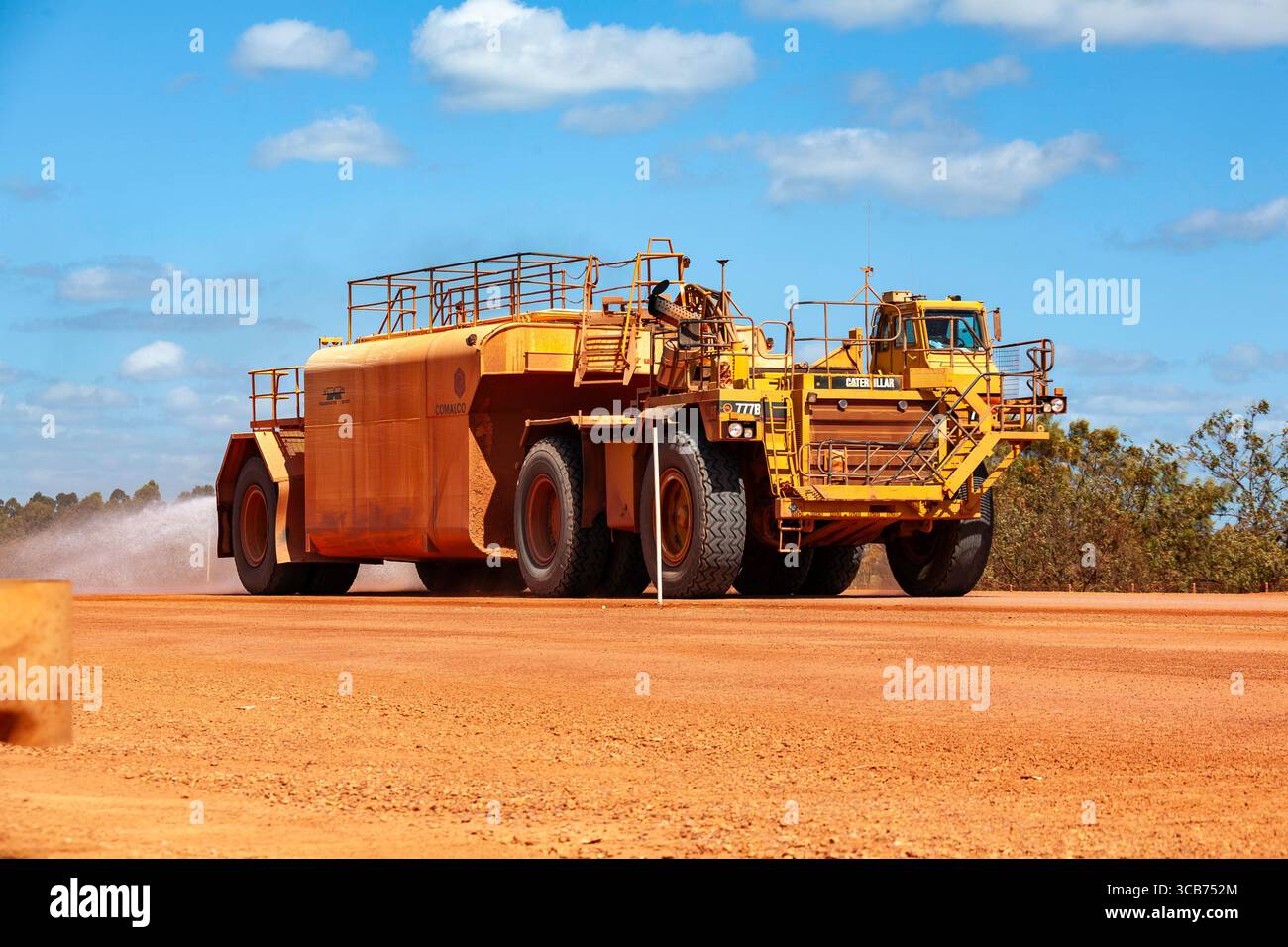 autocisterna in avvicinamento all'irrorazione mineraria verso un enorme camion pesante caterpillar roadmaster sr 150 weipa cape york queensland australia Foto Stock