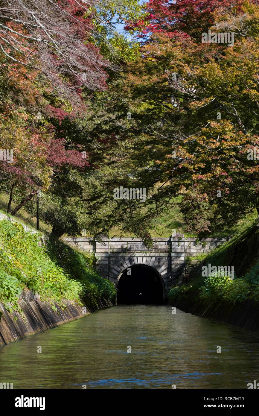 Il tunnel del canale del lago Biwa è circondato da una vegetazione lussureggiante e da vivaci foglie autunnali che si riflettono in un tranquillo corso d'acqua, Kyoto, Giappone Foto Stock