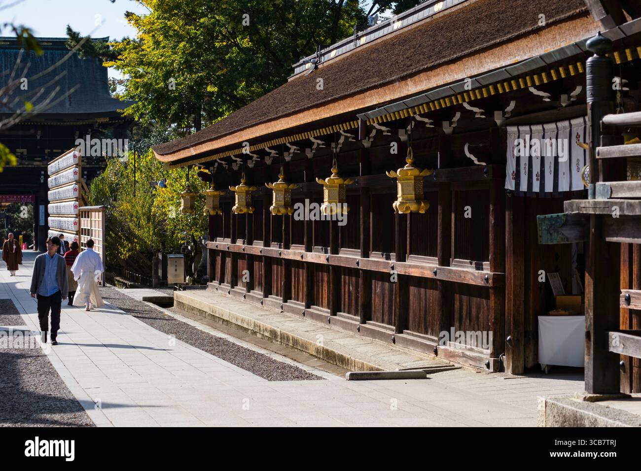 Un tranquillo tempio giapponese con architettura in legno, visitatori che passeggiano e vicine lanterne sospese durante una giornata di sole, Kyoto, Giappone Foto Stock