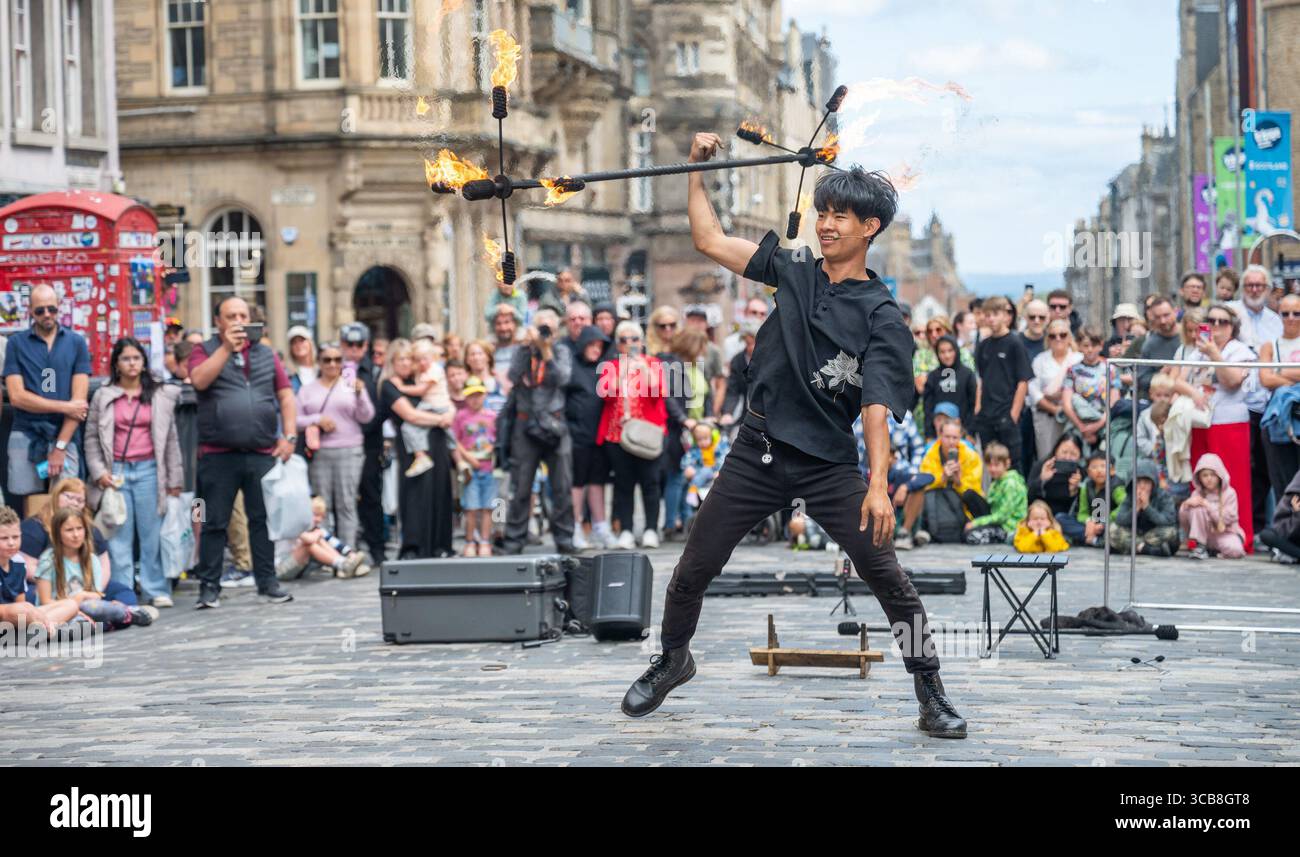 Edimburgo, Regno Unito. 7 agosto 2025. 7 agosto 2025 Edimburgo, Edinburgh Fringe Festival. L'Edinburgh Fringe è ora in pieno svolgimento e la folla si affolla al Royal Mile per sperimentare la varietà di talenti, immagini e suoni degli artisti di strada. Xiao Hei esegue la sua azione di fuoco davanti alla folla PIC Credit: phil wilkinson/Alamy Live News Foto Stock