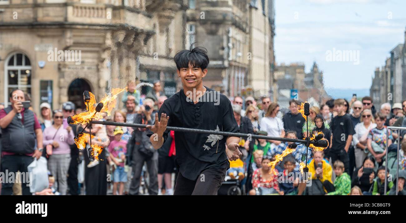 Edimburgo, Regno Unito. 7 agosto 2025. 7 agosto 2025 Edimburgo, Edinburgh Fringe Festival. L'Edinburgh Fringe è ora in pieno svolgimento e la folla si affolla al Royal Mile per sperimentare la varietà di talenti, immagini e suoni degli artisti di strada. Xiao Hei esegue la sua azione di fuoco davanti alla folla PIC Credit: phil wilkinson/Alamy Live News Foto Stock