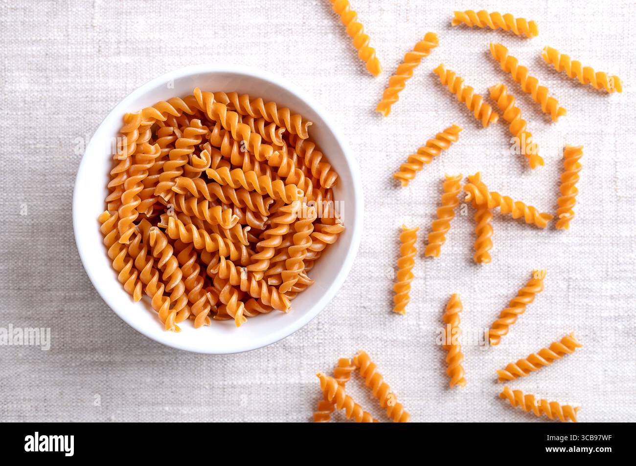 Pasta a spirale di ceci, spaghetti senza glutine in un recipiente bianco su tessuto di lino. Piccoli fusilli, una varietà di pasta, con forma elicoidale o cavatappi. Foto Stock